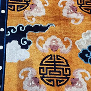 Golden yellow rug detailed with navy circular symbols and stylized white and pink cloud patterns.