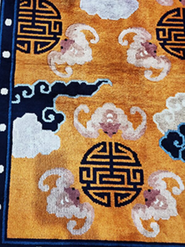 Golden yellow rug detailed with navy circular symbols and stylized white and pink cloud patterns.