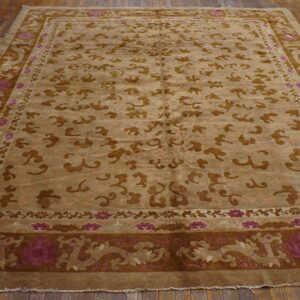 Brown and tan rug featuring stylized cloud patterns and pink floral borders on wood planks.