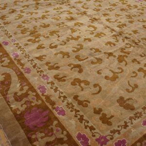 Muted gold cloud motifs cover a tan rug field, accented by a dark brown and magenta floral border.