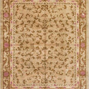 Low-pile tan rug with contrasting brown scrolling motifs and borders accented by bright pink floral designs.