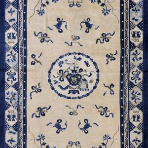 Beige field rug with dark blue motifs, including vases, ribbons, and a complex detailed border pattern.