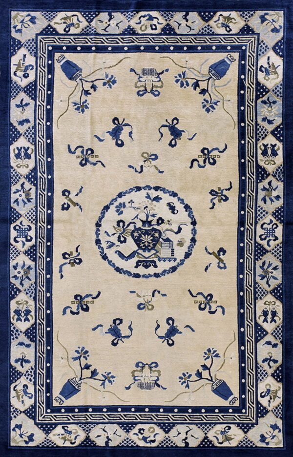 Beige field rug with dark blue motifs, including vases, ribbons, and a complex detailed border pattern.