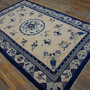 Ivory field rug featuring stylized blue symbols, a central medallion, and multiple patterned borders on wood flooring.