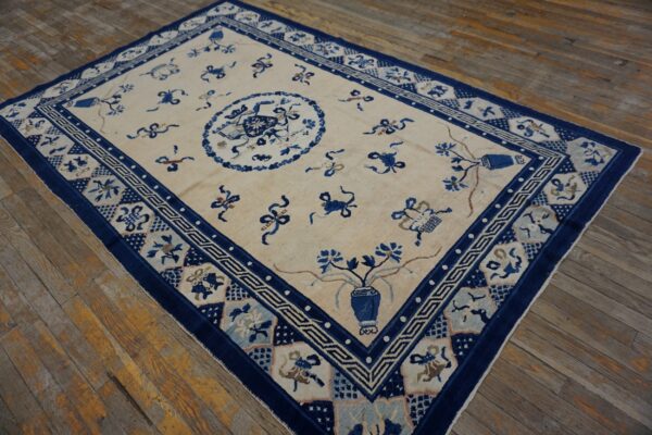 Ivory field rug featuring stylized blue symbols, a central medallion, and multiple patterned borders on wood flooring.