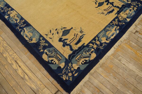 High-pile gold rug with a navy and light blue scenic border rests on worn plank flooring.