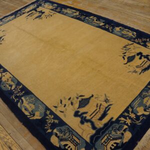 Golden rug with a solid field and wide navy and light blue border featuring stylized scenic patterns.
