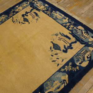 Low-pile gold rug features an intricate navy and blue pictorial border on rustic diagonal wood floors.