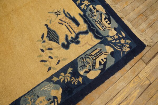 Yellow rug with navy and light blue pictorial borders lies over diagonal distressed wood flooring.