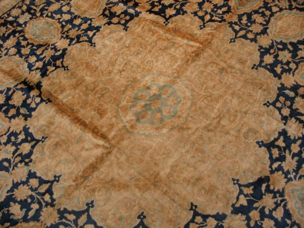 Ornate high-pile rug detail showing a camel-colored medallion surrounded by dark blue and tan floral motifs.