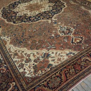 A traditional rug with rust, cream, and navy floral patterns rests on weathered gray wood flooring.