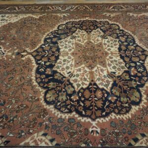 Traditional low-pile rug featuring a navy and cream floral medallion on a rust-colored patterned field.