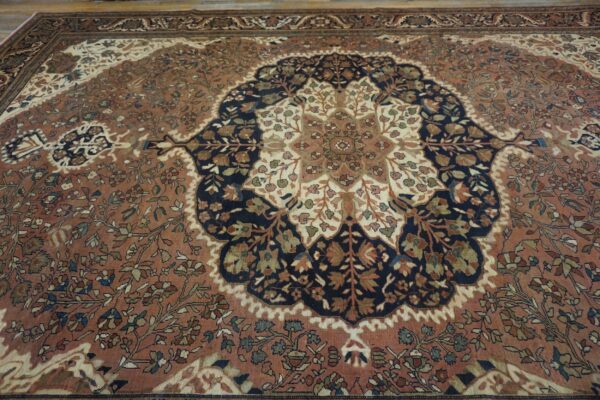 Traditional low-pile rug featuring a navy and cream floral medallion on a rust-colored patterned field.