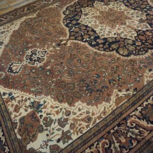 Rust and navy floral patterned rug with an intricate central design on rustic wood floorboards.