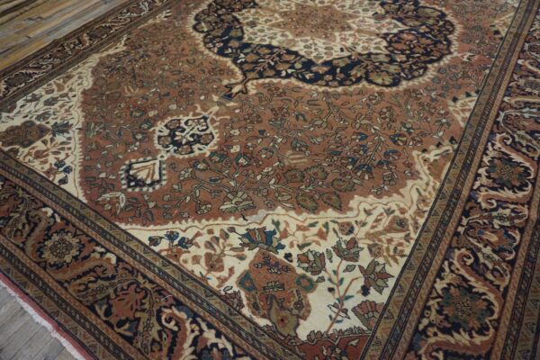 Traditional low-pile rug with rust, cream, and navy floral patterns on light wood floorboards.