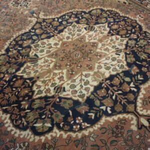 Intricate floral rug featuring a scalloped navy medallion centered on a salmon and cream field.