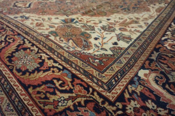 Intricate floral pattern features a cream center field meeting a dark blue and rust colored border.