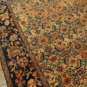 Low-pile rug featuring a dense orange and blue pattern, dark border, resting on worn yellow wood flooring.
