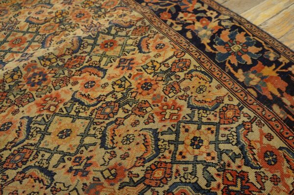Detailed low-pile rug with geometric and floral motifs in beige, rust, and navy on wooden flooring.