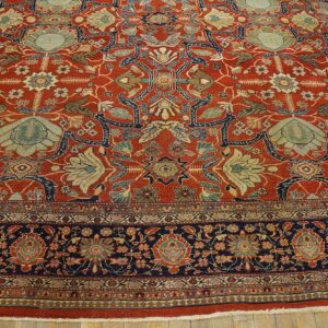 Ornate area rug in rust and navy with elaborate light blue and beige traditional floral designs.