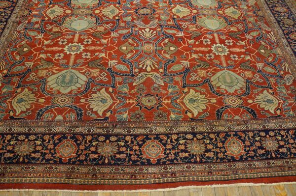 Ornate area rug in rust and navy with elaborate light blue and beige traditional floral designs.