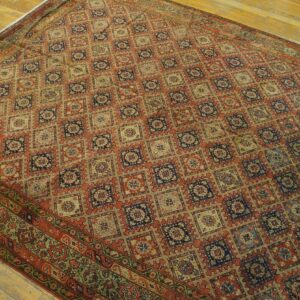 Detailed geometric patterned rug in earth tones, rust, and navy blue lies on light wood flooring.