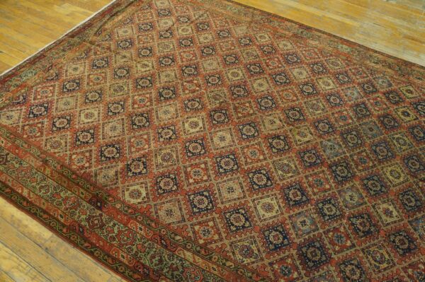 Detailed geometric patterned rug in earth tones, rust, and navy blue lies on light wood flooring.