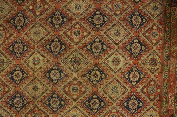Muted rug with a repeating lattice of diamond medallions in rust, deep blue, and olive green.