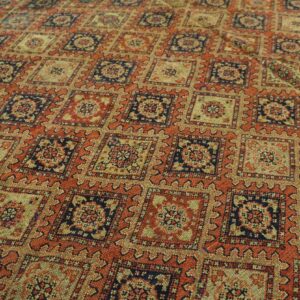 Rustic orange rug with a repeating lattice pattern of navy blue and beige serrated geometric medallions.