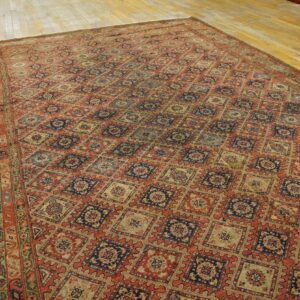 A large rust and blue geometric rug with a diamond lattice pattern covers light hardwood floors.