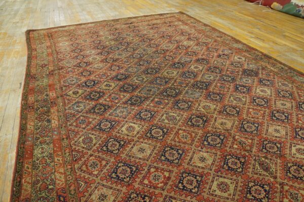 A large rust and blue geometric rug with a diamond lattice pattern covers light hardwood floors.