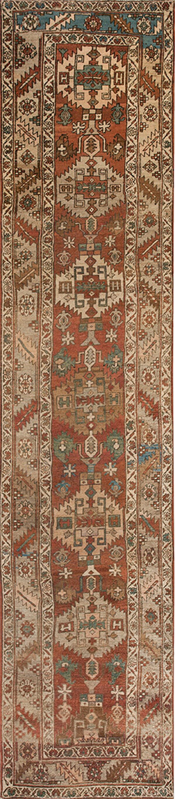 Geometric runner rug with a rust central field, tan borders, and accents of blue and brown.