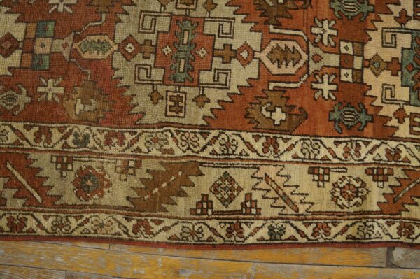 Close-up of a rustic rug with geometric patterns in rust, beige, brown, and hints of teal.