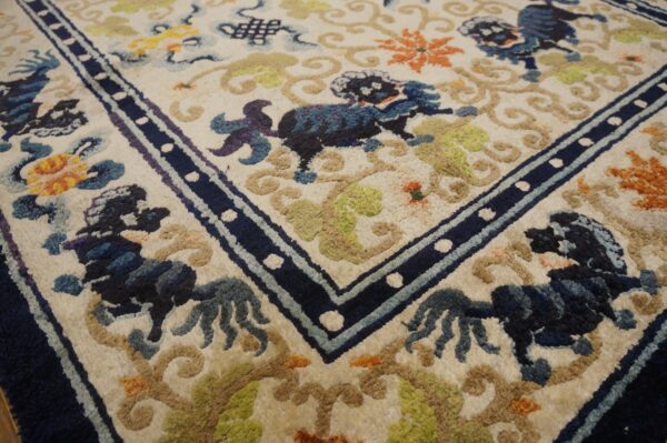 Ivory rug detail showing blue guardian lion motifs, multicolored vines, and a navy blue border with white dots.