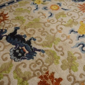 Textured rug featuring a cream background with complex floral designs in blue, rust, yellow, and sage green.