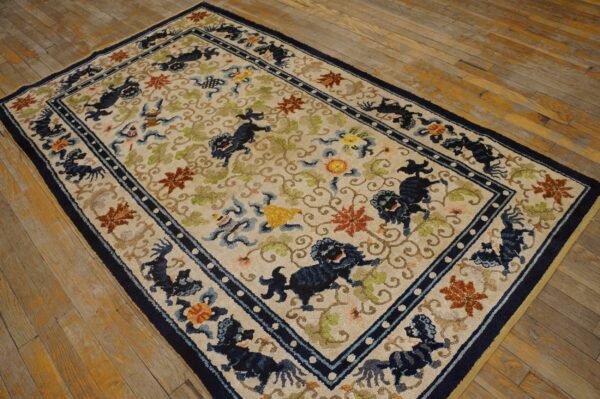 Cream rug with a navy border and stylized blue animal motifs lying on aged hardwood flooring.