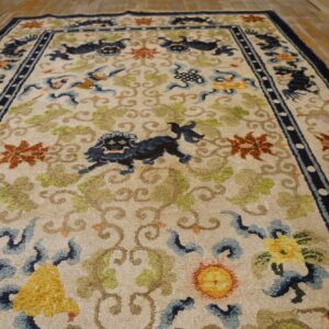 Ivory rug with blue stylized animals, green vines, and orange florals rests on distressed wood flooring.