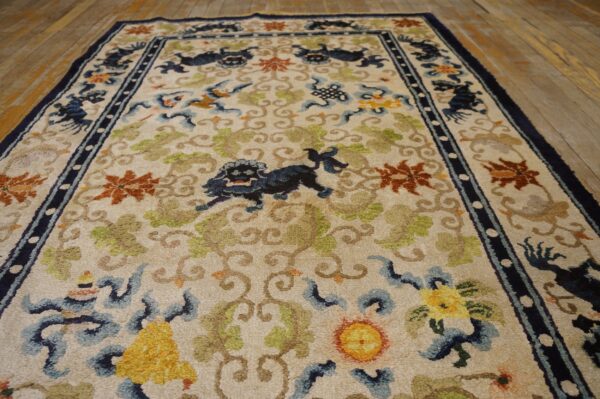 Ivory rug with blue stylized animals, green vines, and orange florals rests on distressed wood flooring.