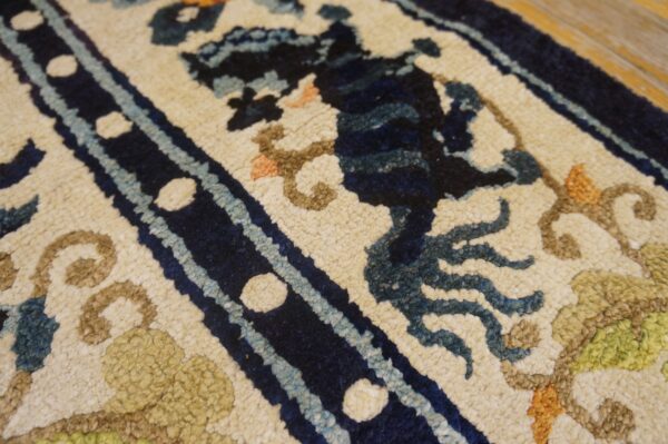 High-pile cream rug with navy, blue, and brown ornamental patterns lying on light wood flooring.