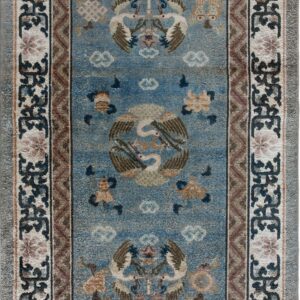Muted blue rug with brown and cream borders, centered with traditional stylized cranes and cloud motifs.