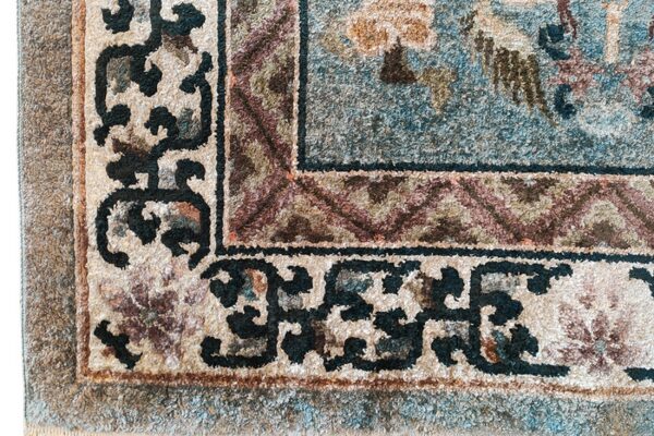 Plush, high-pile rug detail showing teal, beige, and dark brown traditional borders and scrollwork.