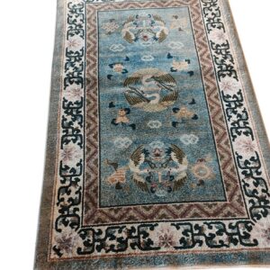 Dusty blue runner rug featuring large pictorial bird designs and complex cream and brown borders.