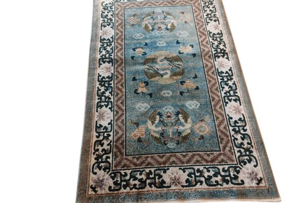 Dusty blue runner rug featuring large pictorial bird designs and complex cream and brown borders.