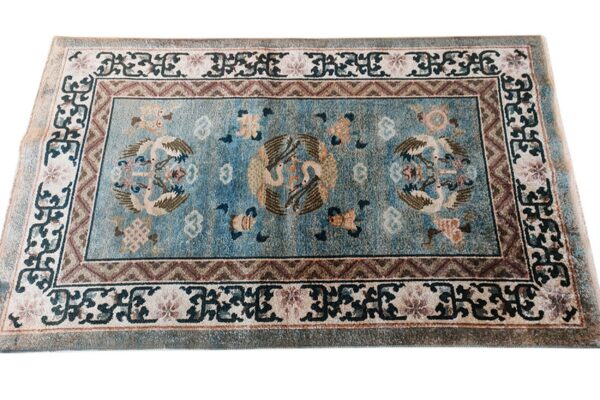 Teal blue rug with an ornate pattern of large stylized birds and complex geometric and floral borders.