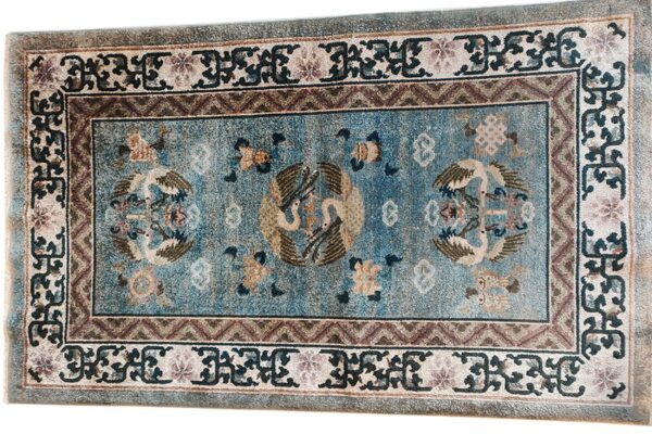 Distressed low-pile rug with a blue field, central bird medallions, and elaborate multi-colored geometric and scrollwork borders.