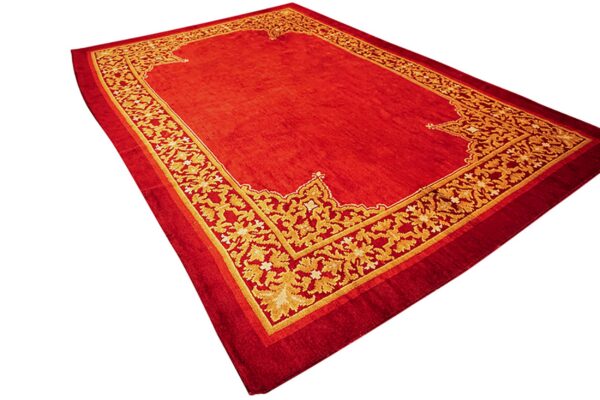 Smooth red rug with a prominent, elaborate golden floral border on all sides.