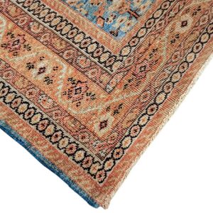 Detailed view of a rug corner featuring orange, tan, and blue colors with multiple geometric and floral borders.