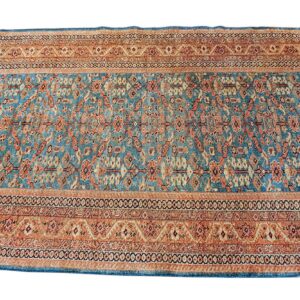 A rectangular rug featuring a dense traditional pattern in teal blue, rust, and beige colors.