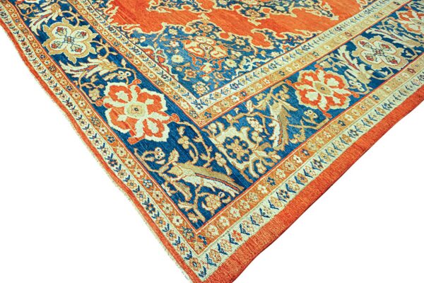 Detailed corner of an ornate rug in rust orange, blue, and cream with complex floral and animal borders.