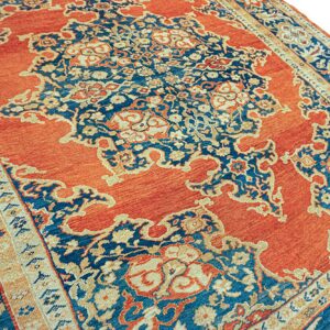 Rust orange rug with a traditional, complex deep blue and cream floral medallion design.